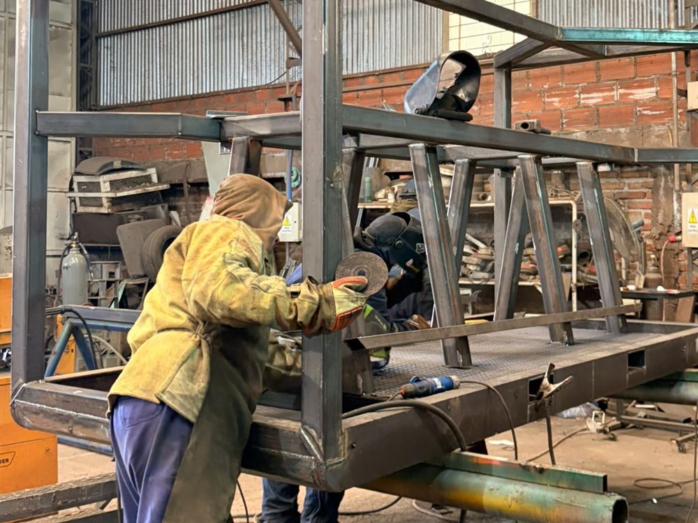 Operario amolando una estructura de caño en el taller